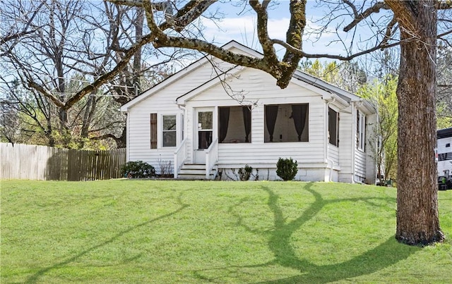 bungalow-style house featuring entry steps, a front lawn, and fence