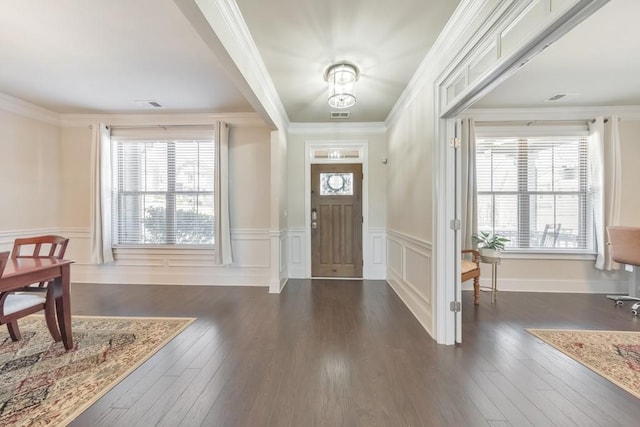 entryway with a wainscoted wall, dark wood-style floors, visible vents, and ornamental molding