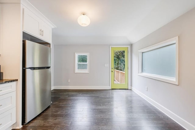 kitchen with white cabinets, dark hardwood / wood-style floors, dark stone countertops, and stainless steel fridge