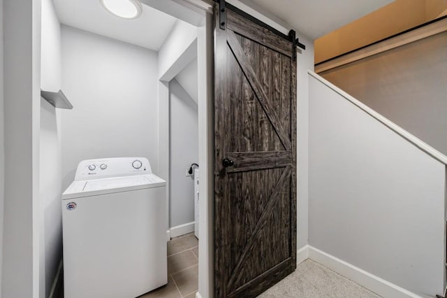 laundry room featuring a barn door, washer / clothes dryer, and light tile patterned flooring