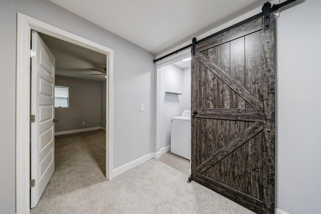 hall with washer / clothes dryer, light colored carpet, and a barn door