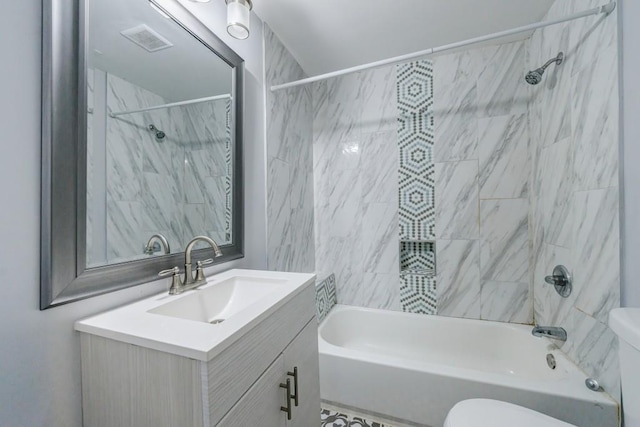 full bathroom featuring tiled shower / bath, vanity, and toilet