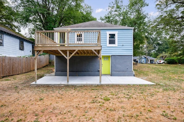 back of property with a deck, a patio area, and a lawn