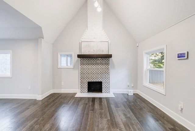 unfurnished living room featuring dark wood-type flooring, a large fireplace, and high vaulted ceiling