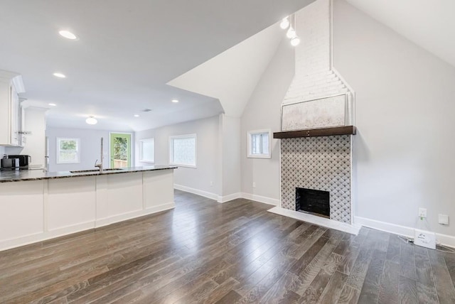 unfurnished living room with a healthy amount of sunlight, dark hardwood / wood-style floors, sink, and a fireplace