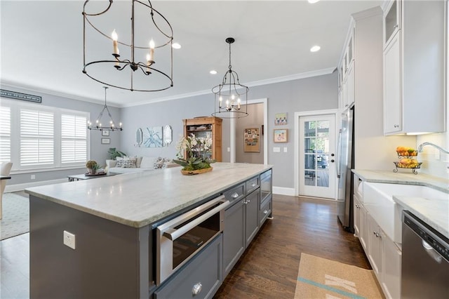 kitchen featuring a kitchen island, stainless steel appliances, decorative light fixtures, dark hardwood / wood-style flooring, and white cabinetry