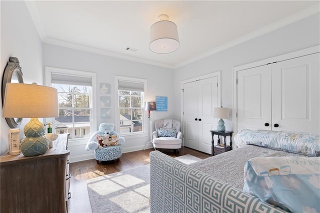 bedroom with crown molding, dark hardwood / wood-style flooring, and multiple closets