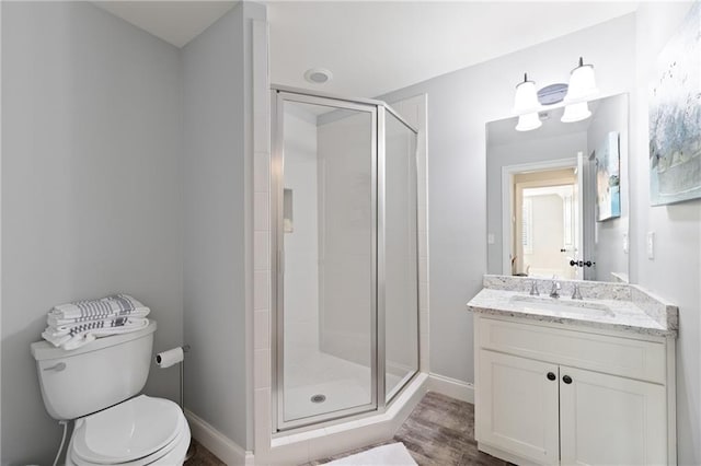 bathroom featuring hardwood / wood-style flooring, a shower with shower door, large vanity, and toilet