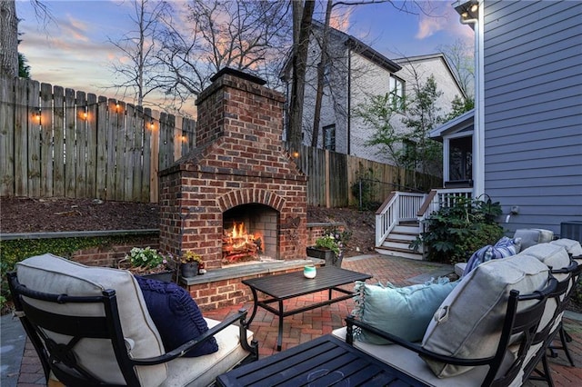 patio terrace at dusk with an outdoor living space with a fireplace