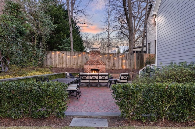 patio terrace at dusk with an outdoor fireplace