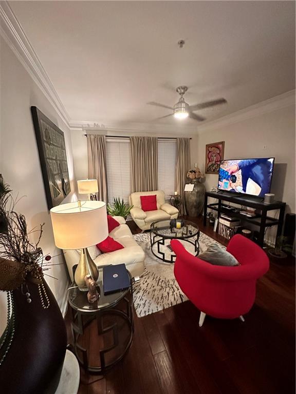 living room featuring ceiling fan, wood-type flooring, and crown molding