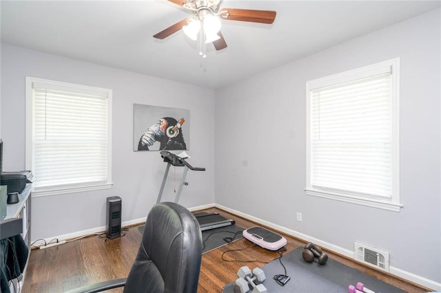 exercise room featuring visible vents, wood finished floors, baseboards, ceiling fan, and a wealth of natural light