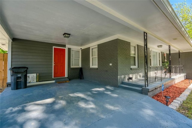 doorway to property featuring a porch and brick siding