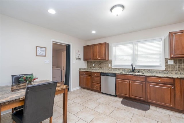 kitchen with stainless steel dishwasher, backsplash, washer / dryer, and a sink