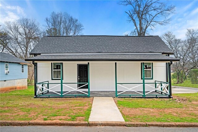 view of front of home with cooling unit, a front yard, and covered porch