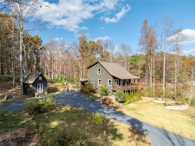 view of side of property with a wooden deck, a yard, and a shed