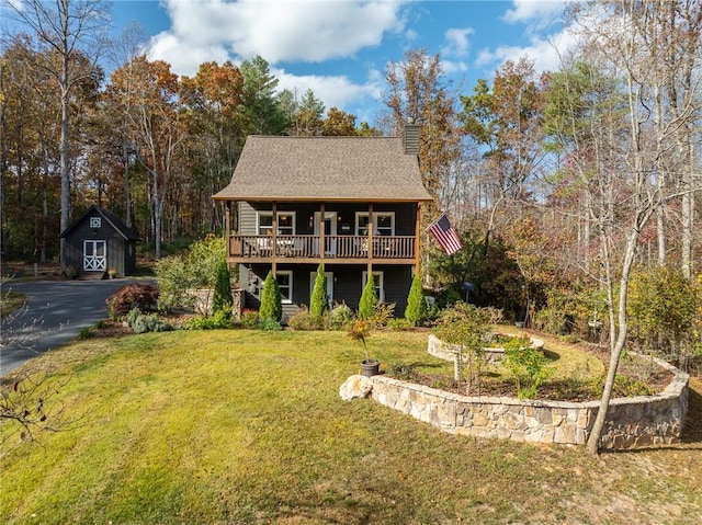 view of front of property featuring a front lawn and a storage shed