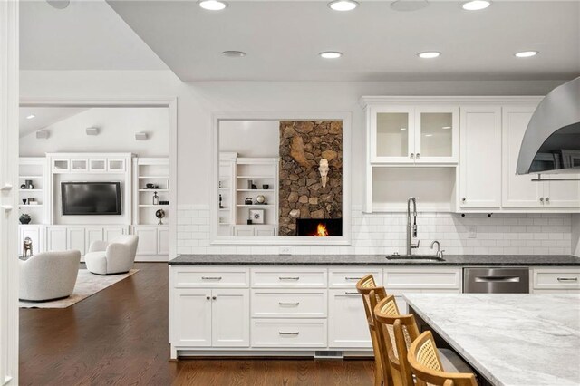 kitchen with dark stone counters, sink, dark wood-type flooring, decorative backsplash, and stainless steel dishwasher