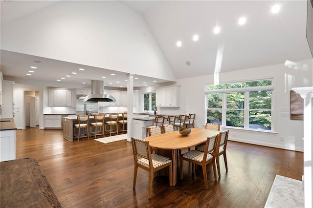 dining room with ornate columns, high vaulted ceiling, and dark wood-type flooring