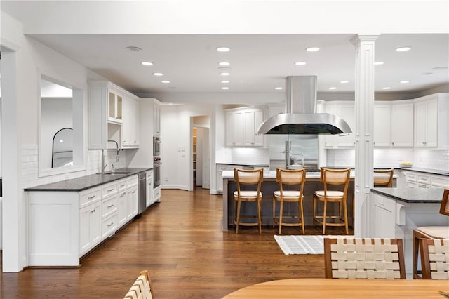 kitchen featuring a breakfast bar area, tasteful backsplash, extractor fan, and dark hardwood / wood-style flooring