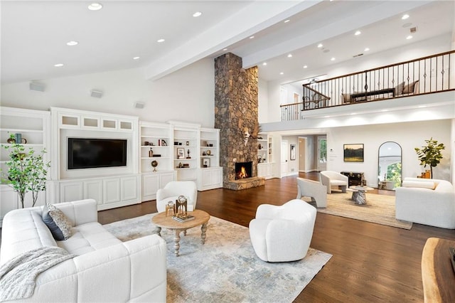 living room featuring dark hardwood / wood-style flooring, beam ceiling, high vaulted ceiling, and a stone fireplace