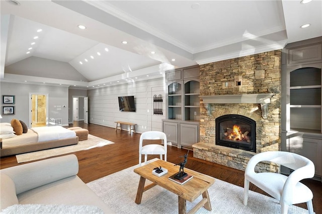 living room with built in shelves, crown molding, hardwood / wood-style floors, and a stone fireplace