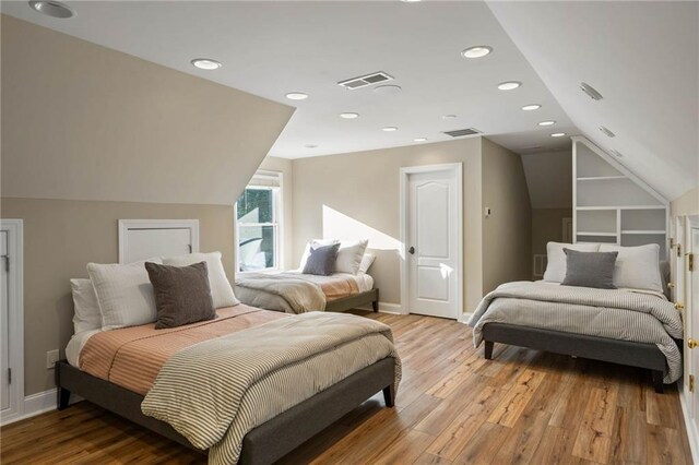 bedroom with light wood-type flooring and vaulted ceiling