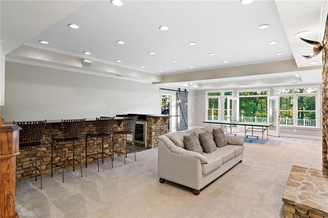 living room featuring a raised ceiling, ornamental molding, light carpet, and a barn door