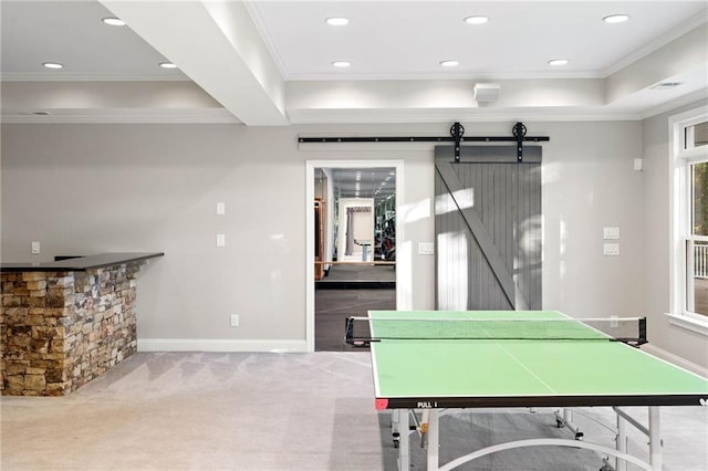 game room with carpet, a raised ceiling, a barn door, and ornamental molding