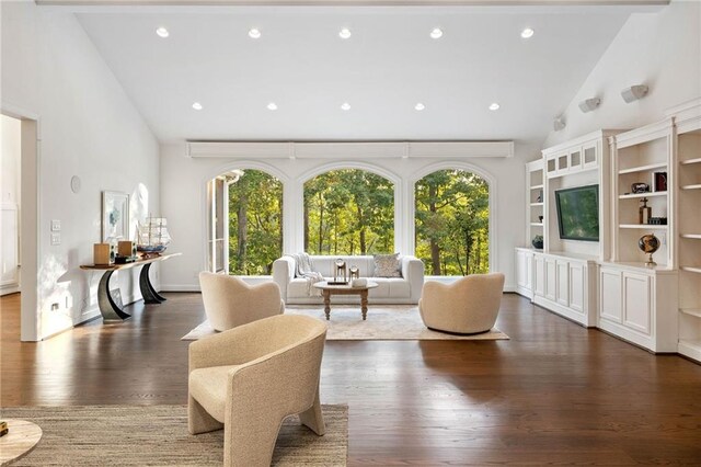 living room with a wealth of natural light, high vaulted ceiling, dark wood-type flooring, and beamed ceiling