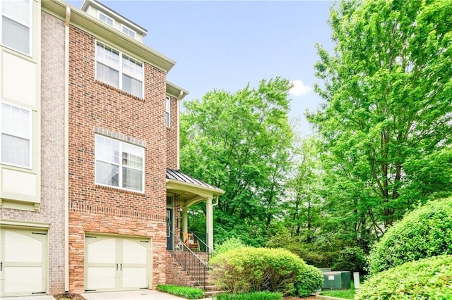 1996 Cobblestone Cir NE, Atlanta, GA 30319 - view of home's exterior featuring an attached garage, driveway, a standing seam roof, stairs, and brick siding