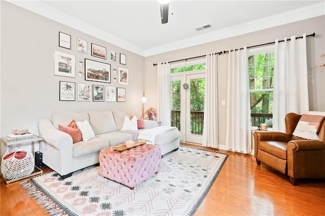 living room with plenty of natural light, wood finished floors, and ornamental molding
