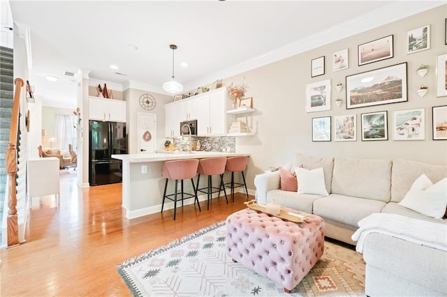 living area featuring ornamental molding, light wood-type flooring, and recessed lighting