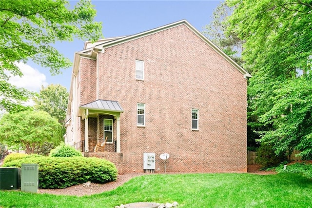 view of home's exterior featuring brick siding, a yard, and a standing seam roof