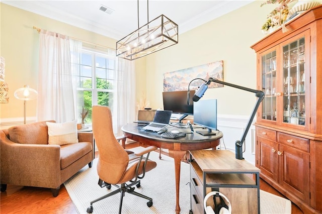 home office featuring a chandelier, light wood-style floors, crown molding, and wainscoting