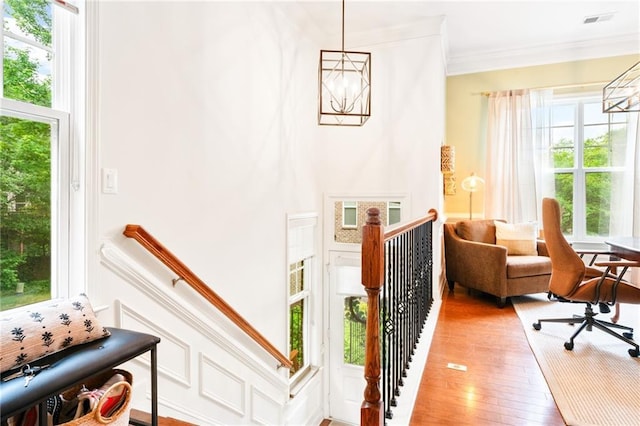 living area with an upstairs landing, a chandelier, crown molding, and light wood-style flooring