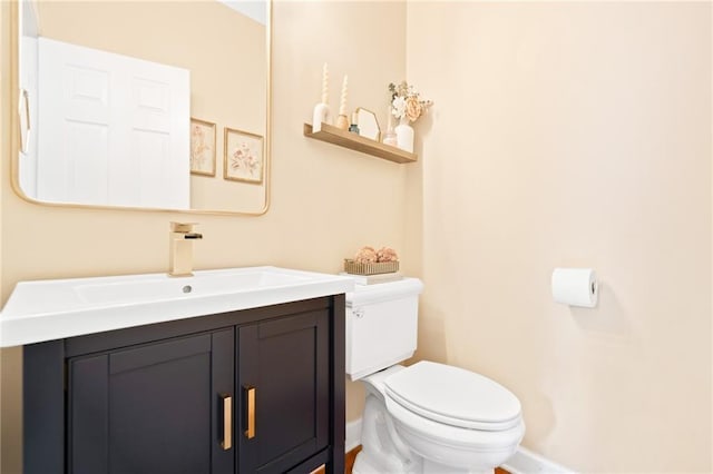 half bath featuring toilet, baseboards, and vanity