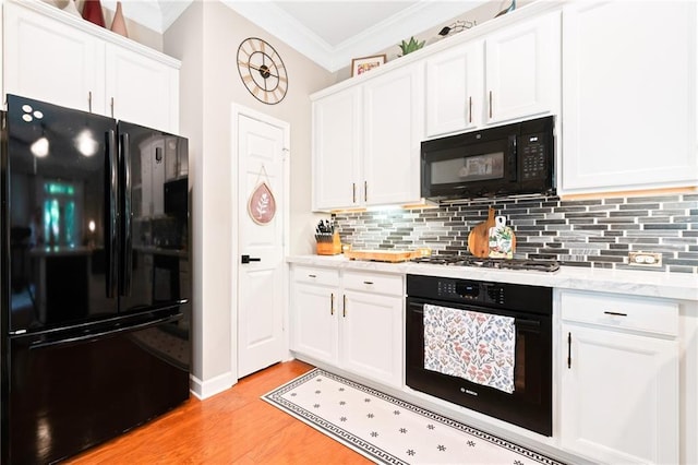 kitchen featuring black appliances, ornamental molding, light wood-style flooring, white cabinets, and tasteful backsplash