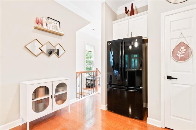 kitchen with freestanding refrigerator, crown molding, light wood-style flooring, white cabinetry, and baseboards