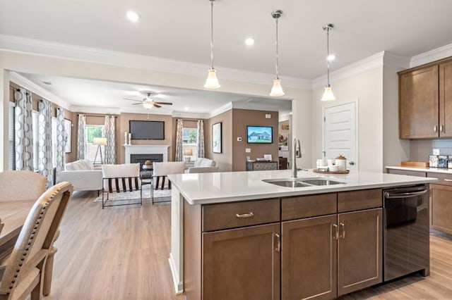 kitchen featuring light wood-style floors, an island with sink, light countertops, a sink, and dishwasher