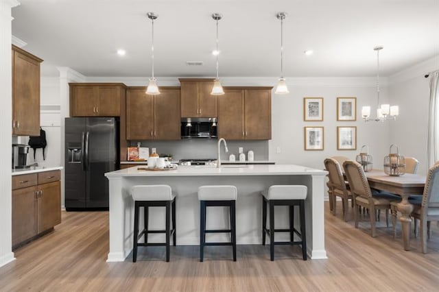 kitchen with stainless steel microwave, a breakfast bar, light wood-type flooring, and black fridge with ice dispenser