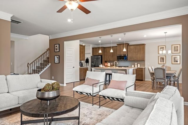 living area featuring visible vents, stairs, baseboards, ceiling fan, and light wood-type flooring