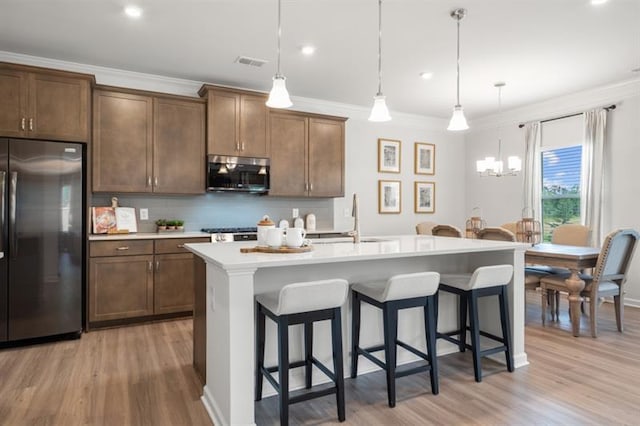 kitchen with visible vents, a kitchen bar, a sink, light wood-style flooring, and stainless steel appliances