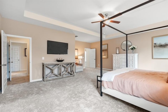 carpeted bedroom featuring a raised ceiling and baseboards