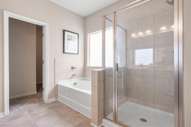 bathroom with baseboards, a stall shower, and a garden tub