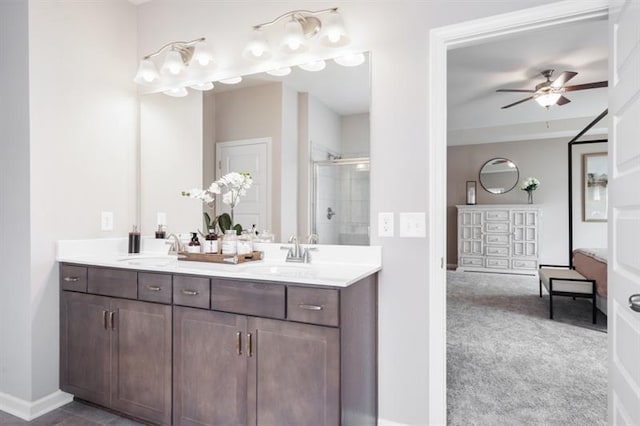 full bath with double vanity, a ceiling fan, a shower stall, and a sink