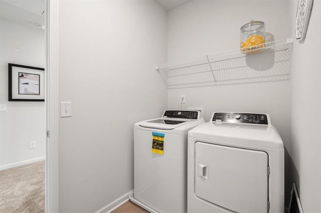 laundry area featuring washing machine and clothes dryer, laundry area, light carpet, and baseboards