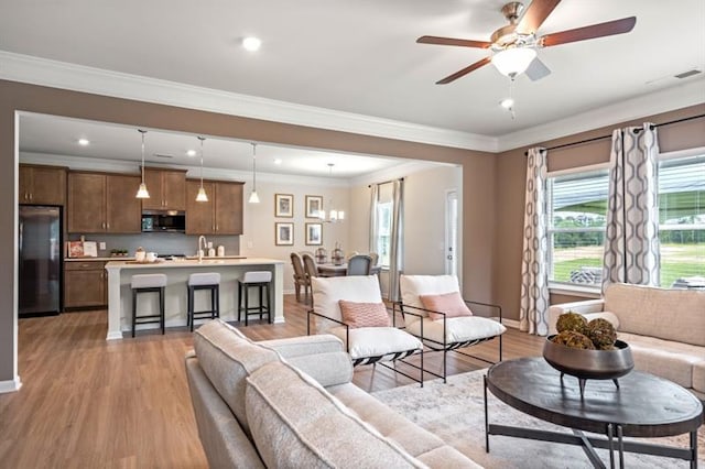 living room with ceiling fan, a wealth of natural light, and light wood-type flooring