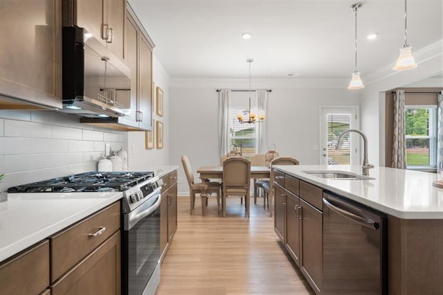 kitchen featuring a sink, light wood-style floors, light countertops, stainless steel appliances, and backsplash