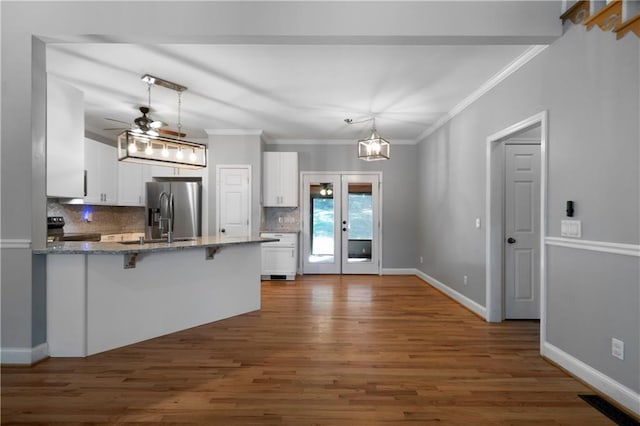 kitchen with stainless steel refrigerator with ice dispenser, black / electric stove, kitchen peninsula, decorative light fixtures, and white cabinets